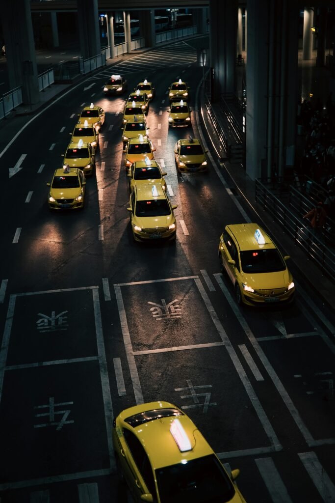 pexels-photo-15509461-15509461 High angle view of lined yellow taxis on urban street during nighttime.